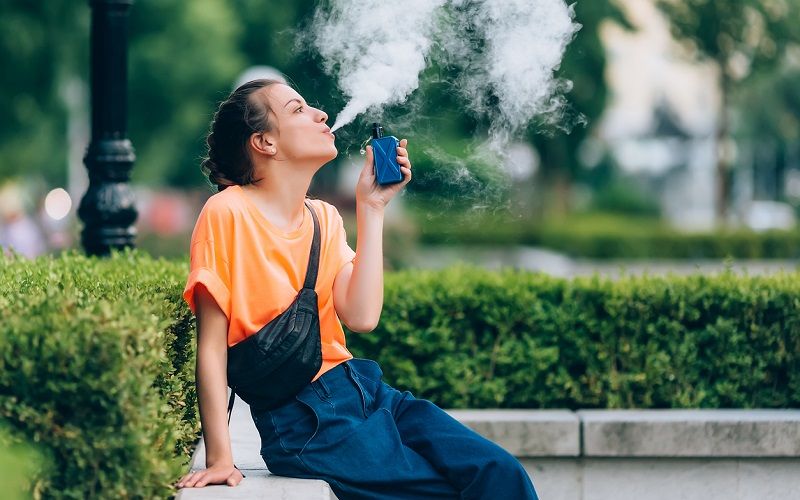 Una mujer joven vapeando en la calle