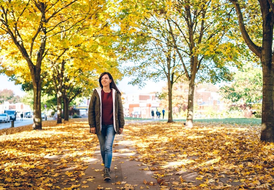 Una mujer joven paseando por un parque en otoño