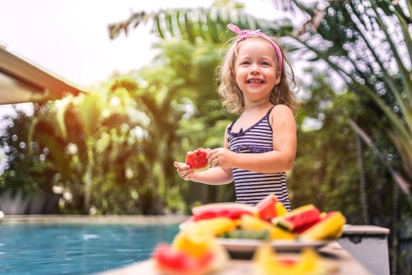 Niña en la piscina comiendo sandía