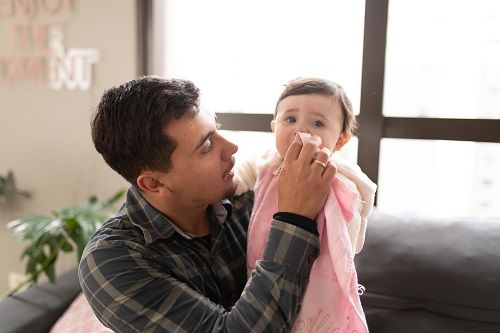 Un padre cuidando de su hija resfriada
